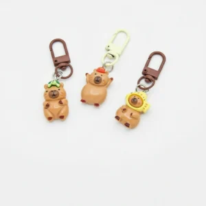 Group of 5 resin capybara keychains wearing turtle hat, flower hood, and bowtie accessories.