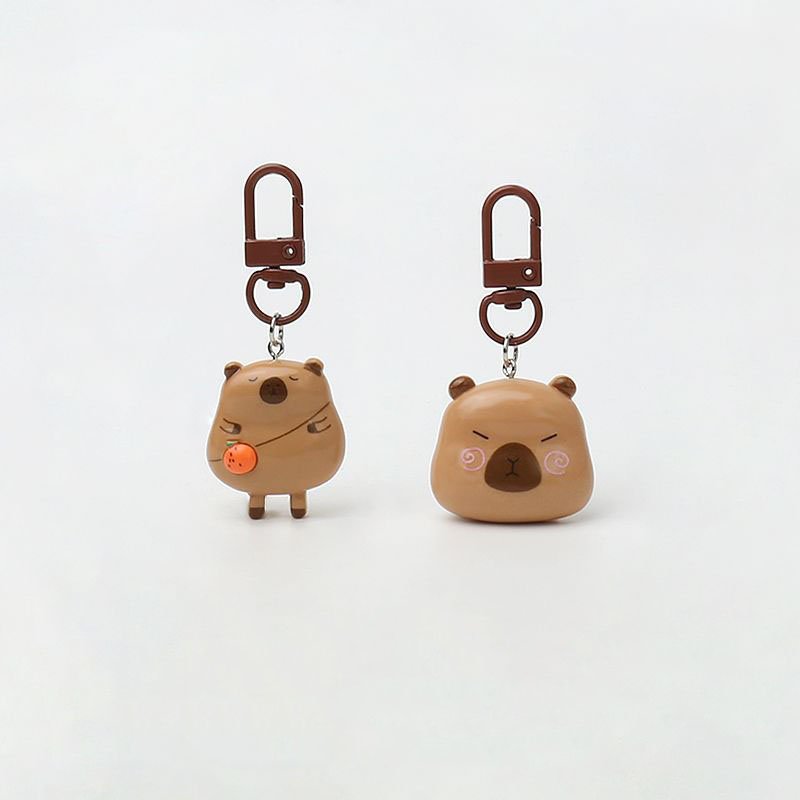 Set of 2 cute resin capybara bag charms with brown clasps and orange accessory.