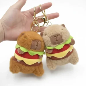 Two sitting capybara burger plush keychains in brown and beige colors held by hand, showing gold metal clasps.