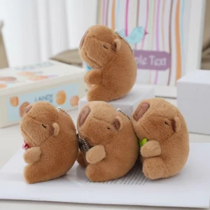 Four sitting capybara plush keychains arranged together, each wearing a different colored bow tie (pink, blue, brown, green).