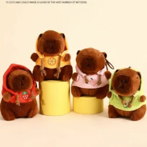 Four capybara plush keychains sitting together wearing red, green, orange, and pink hoodies with fruit embroidery.