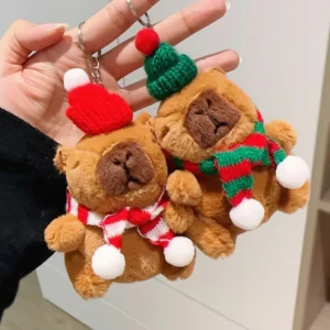 Two Christmas capybara plush toys hanging from a pine tree branch as an ornament.