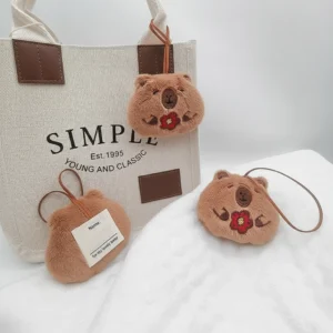 Front view of capybara plush holding a red flower and back view showing the white write-on name label.